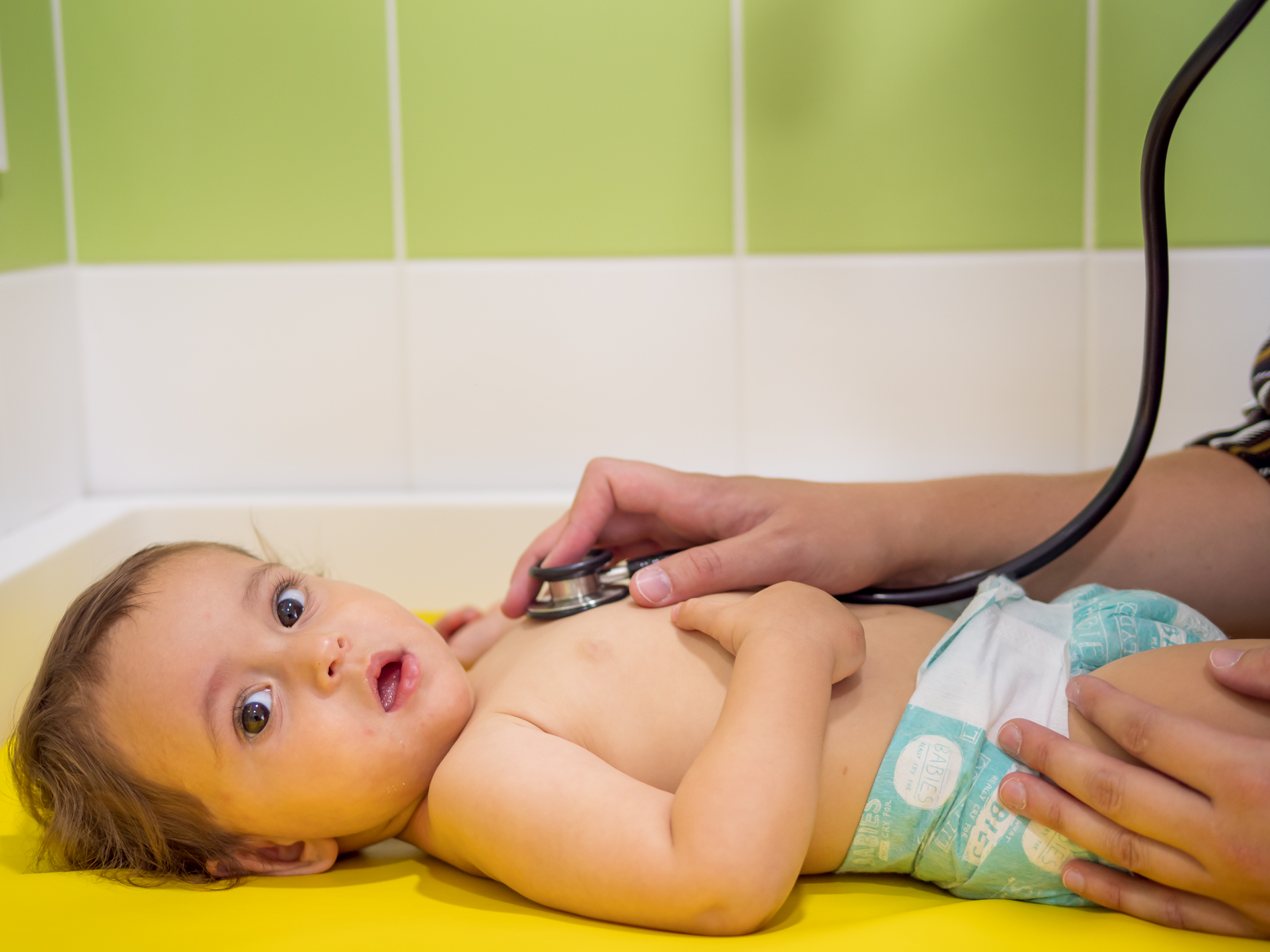 Une petite fille se fait ausculter par le médecin de crèche. On voit ici le stéthoscope. L’enfant est calme et détendue. 