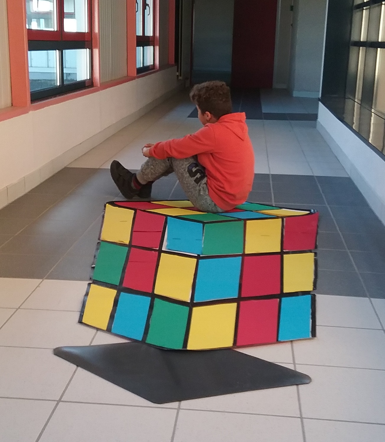 Un enfant assis dans le couloir sur un cube