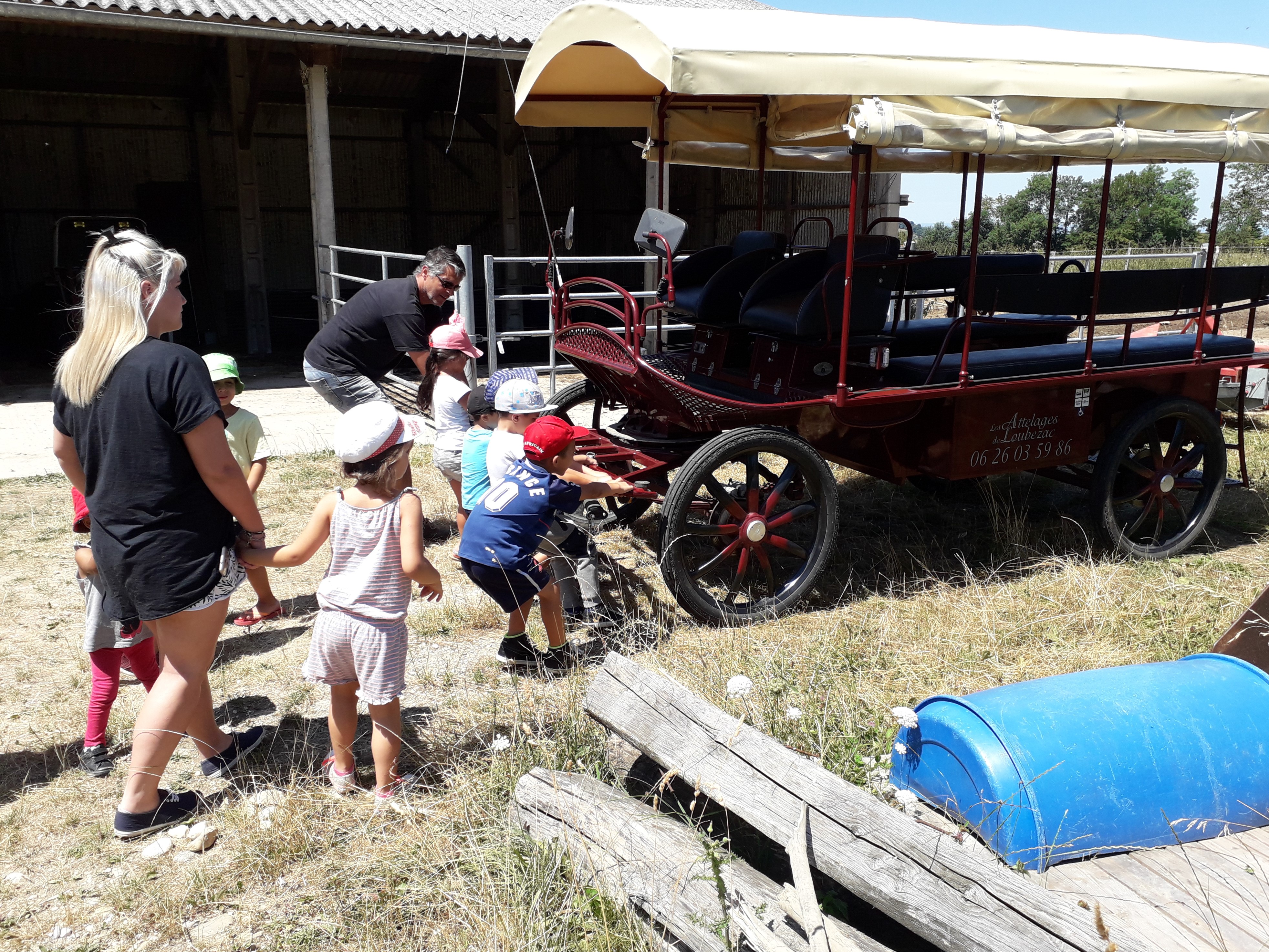 Des enfants à la ferme devant un chariot