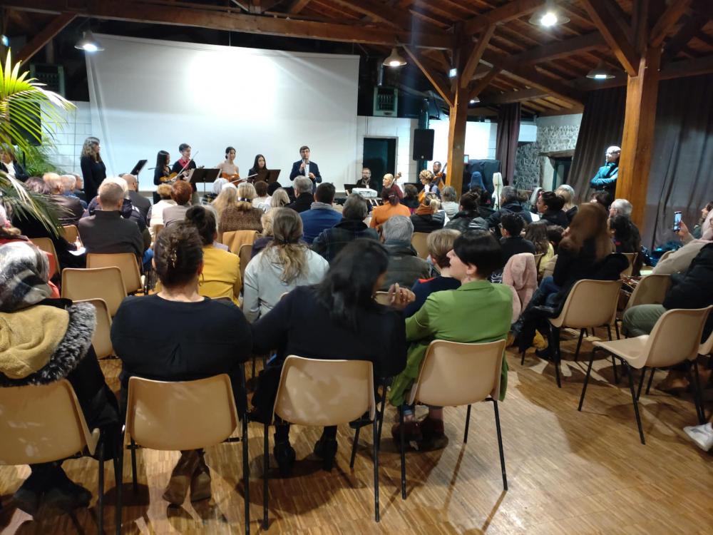 Des dizaines de personnes assistent, assis, aux vœux du maire de Vienne dans la salle de réception du centre social Malissol; un orchestre est sur scène avec lui